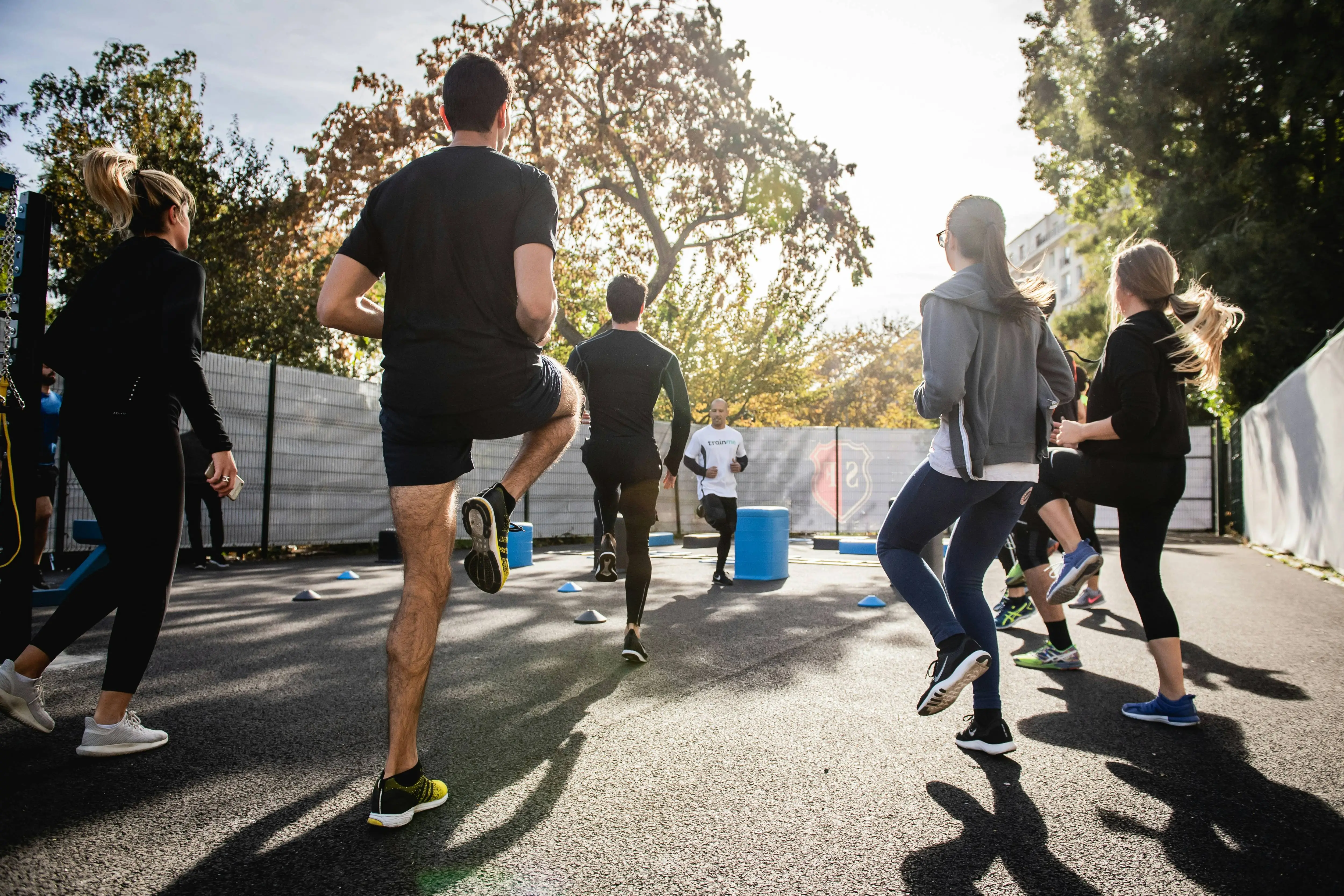 Eine Gruppe von Menschen steht im draußen im Kreis und macht Fitnessübungen