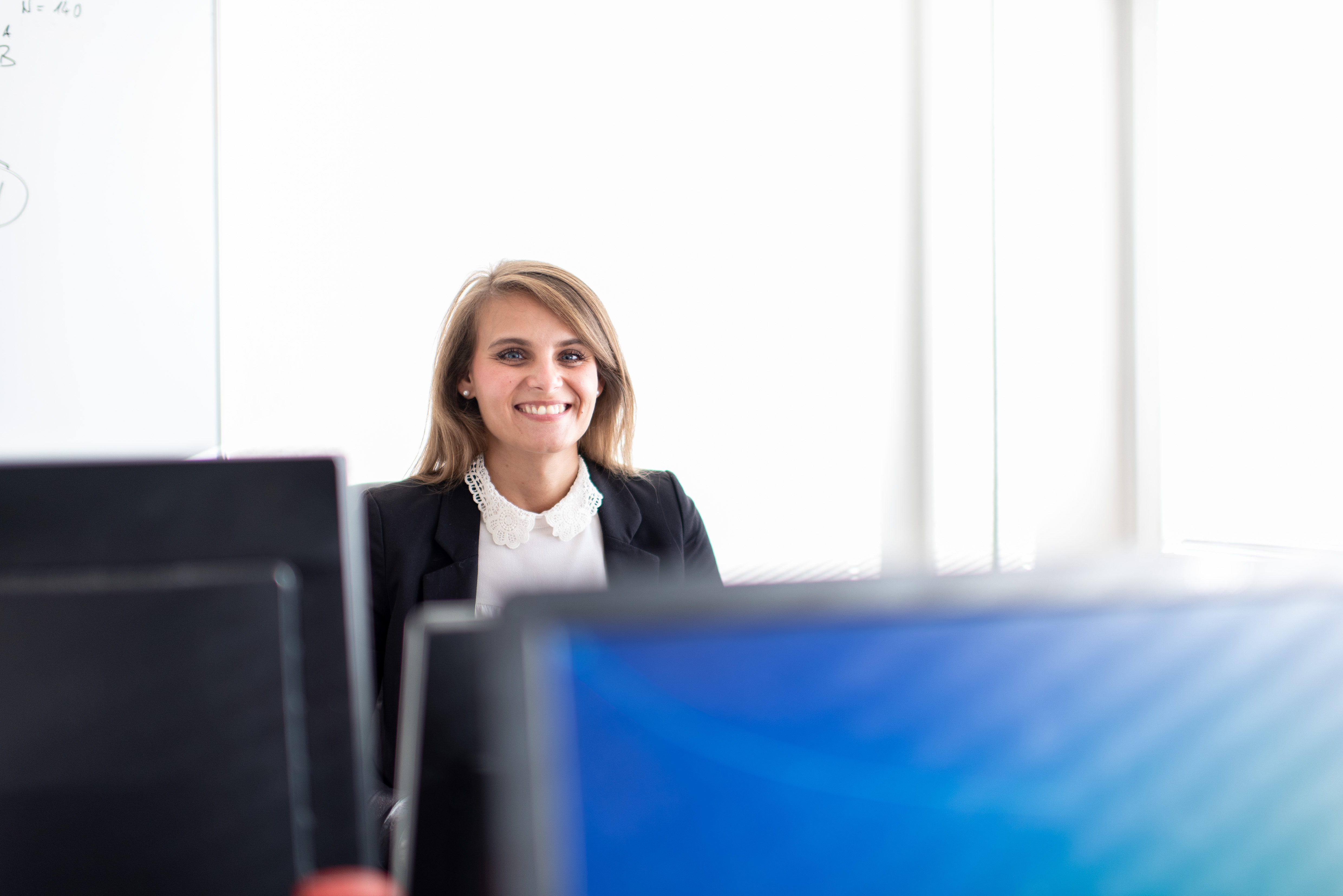 Eine Frau steht lachend vor einem Computer Bildschirm.