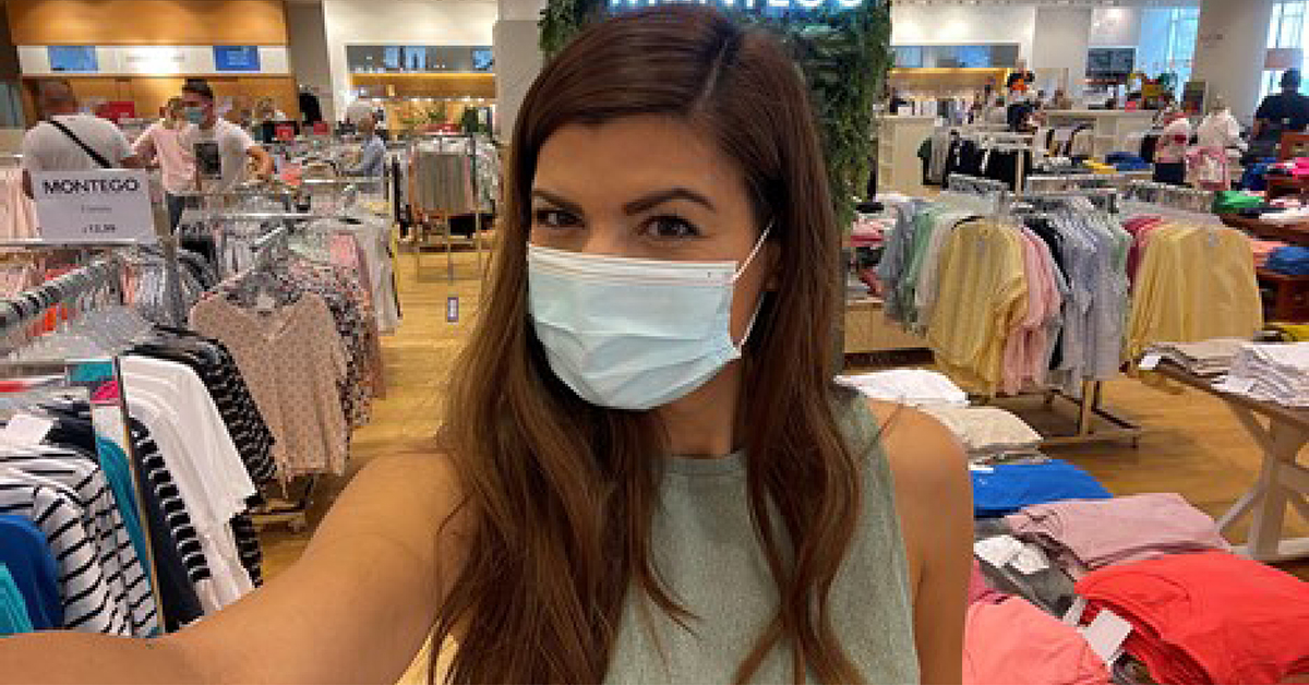 Deana macht ein Selfie von sich mit medizinischer Maske im Verkaufshaus